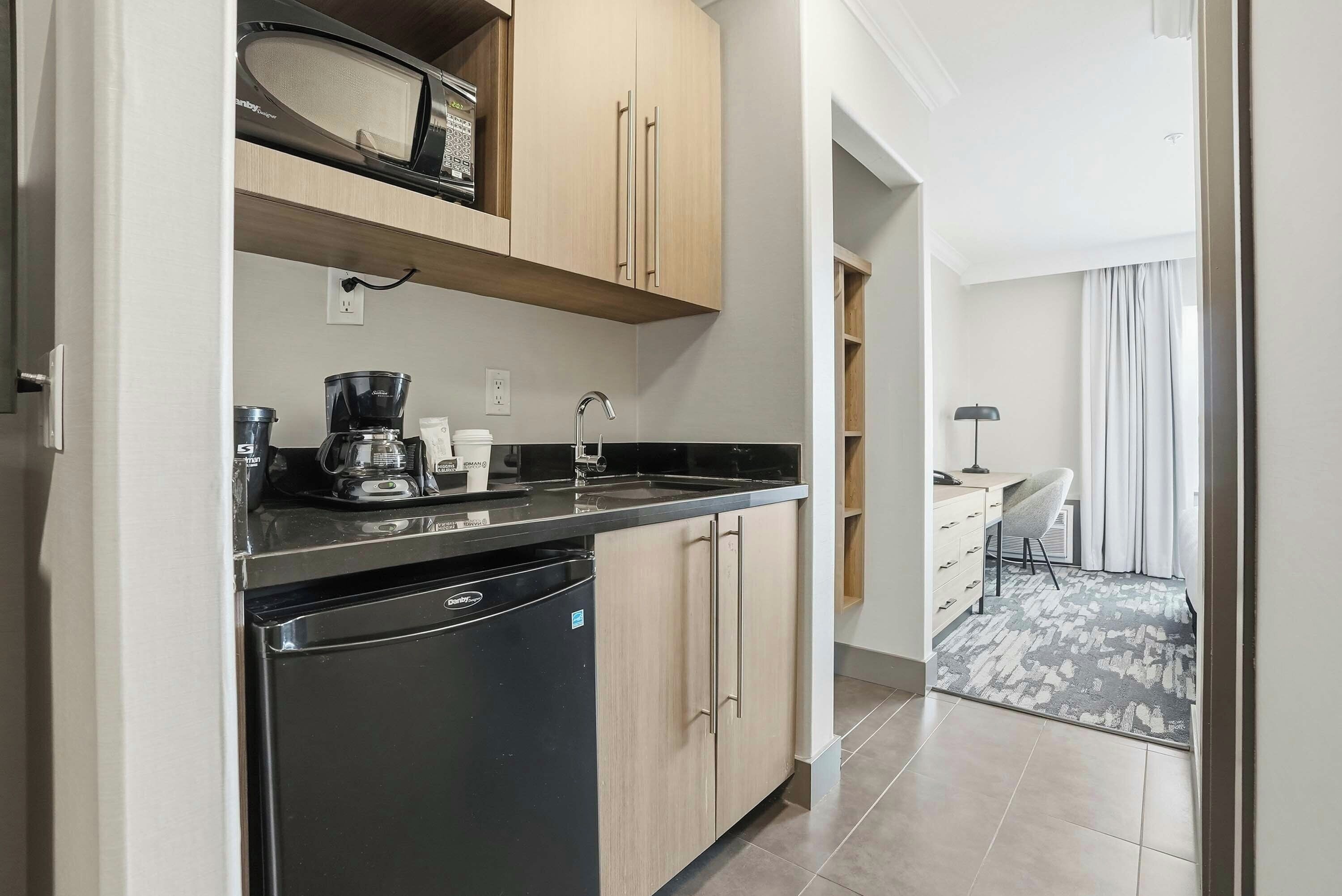 A compact kitchen with a dishwasher, a coffee maker, and a microwave.