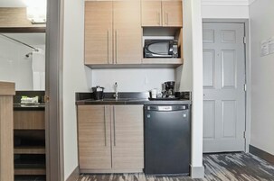 Una cocina compacta con armarios de madera, microondas, cafetera y lavavajillas.