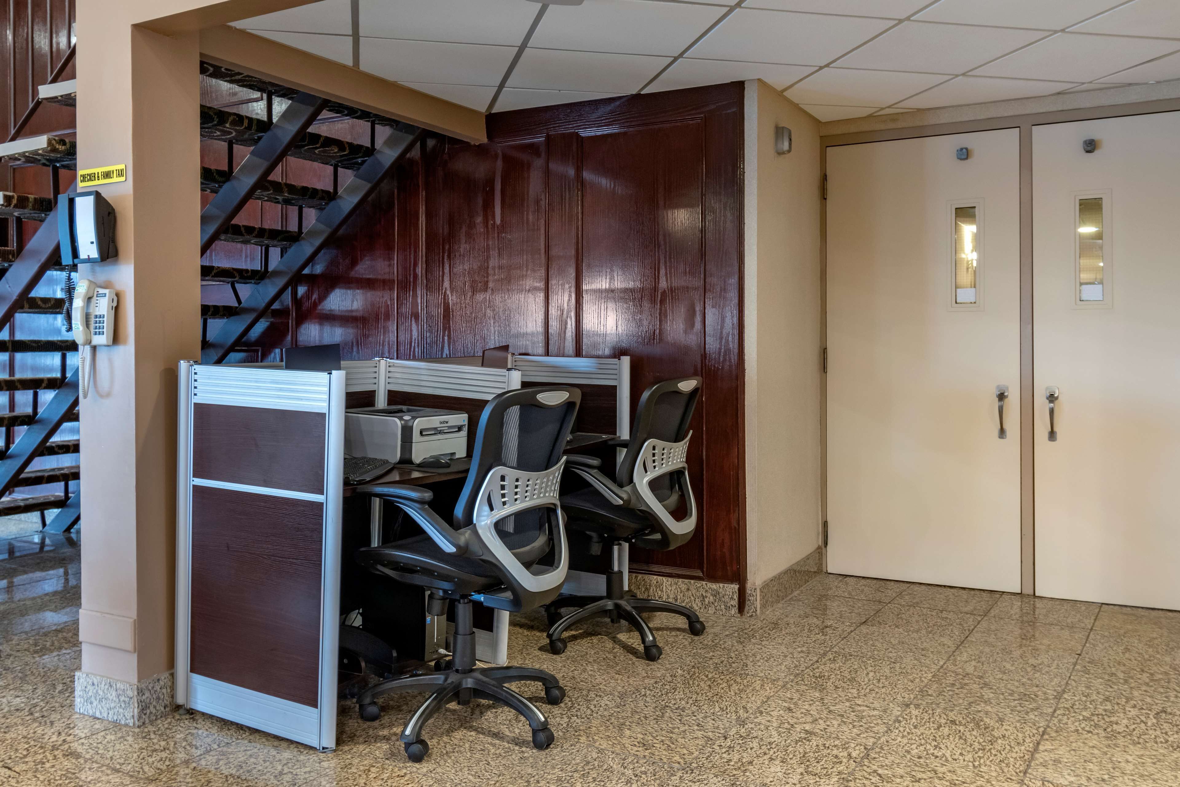 A conference room with a desk, chairs, a phone, and a staircase.