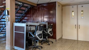 A conference room with a desk, chairs, a phone, and a staircase.
