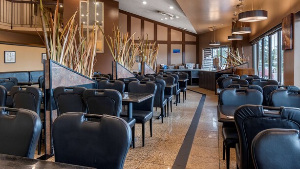 A restaurant with black leather chairs, a staircase, and large windows. - Best Western Marquis Inn & Suites (Prince Albert)