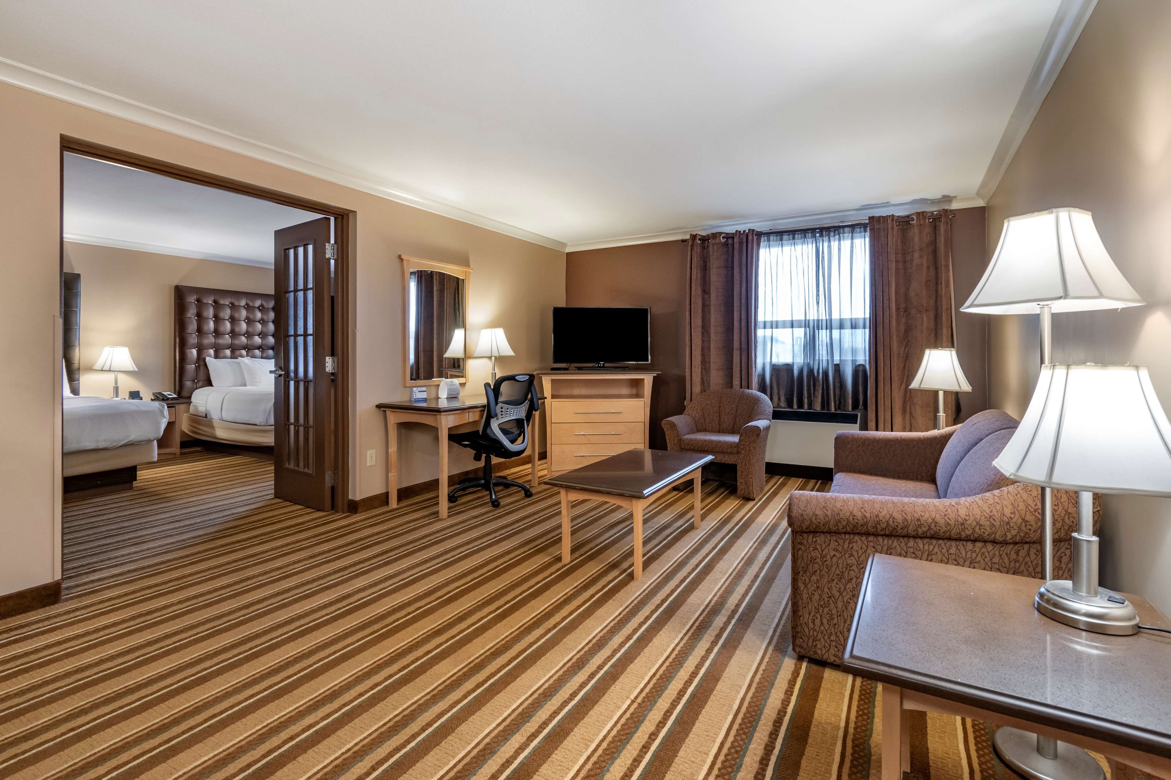 A hotel room with a bed, a desk, a television, a sofa, and a chair.
