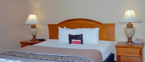 A hotel room with a large bed, two bedside tables, and lamps.