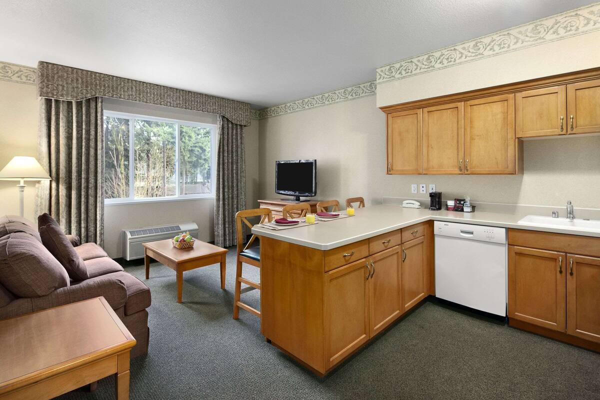 A compact living space with a kitchenette, a dining area, and a seating area with a sofa and a table.