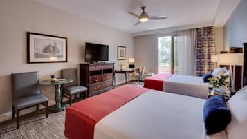 Habitación de hotel con dos camas, un escritorio con computadora, televisión, una silla y una mesita.