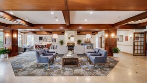 A spacious living area with a fireplace, two armchairs, a coffee table, and a large rug.