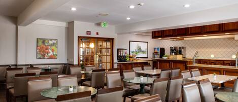 A restaurant with multiple tables and chairs, a kitchen area, and an exit sign.