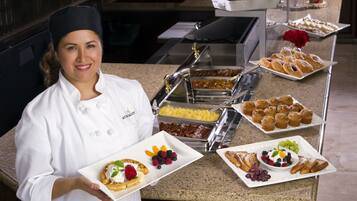 Montaje de bufé con diversas opciones de comida, incluyendo gofres, pastelería y frutas.