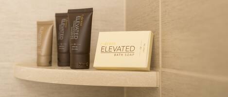 Un estante en el baño con tres botellas de jabón de baño y una caja con la etiqueta 'Elevated Bath Soap'.