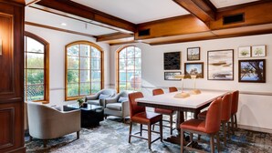 A spacious room with a large table and chairs, large windows, and artwork on the walls.