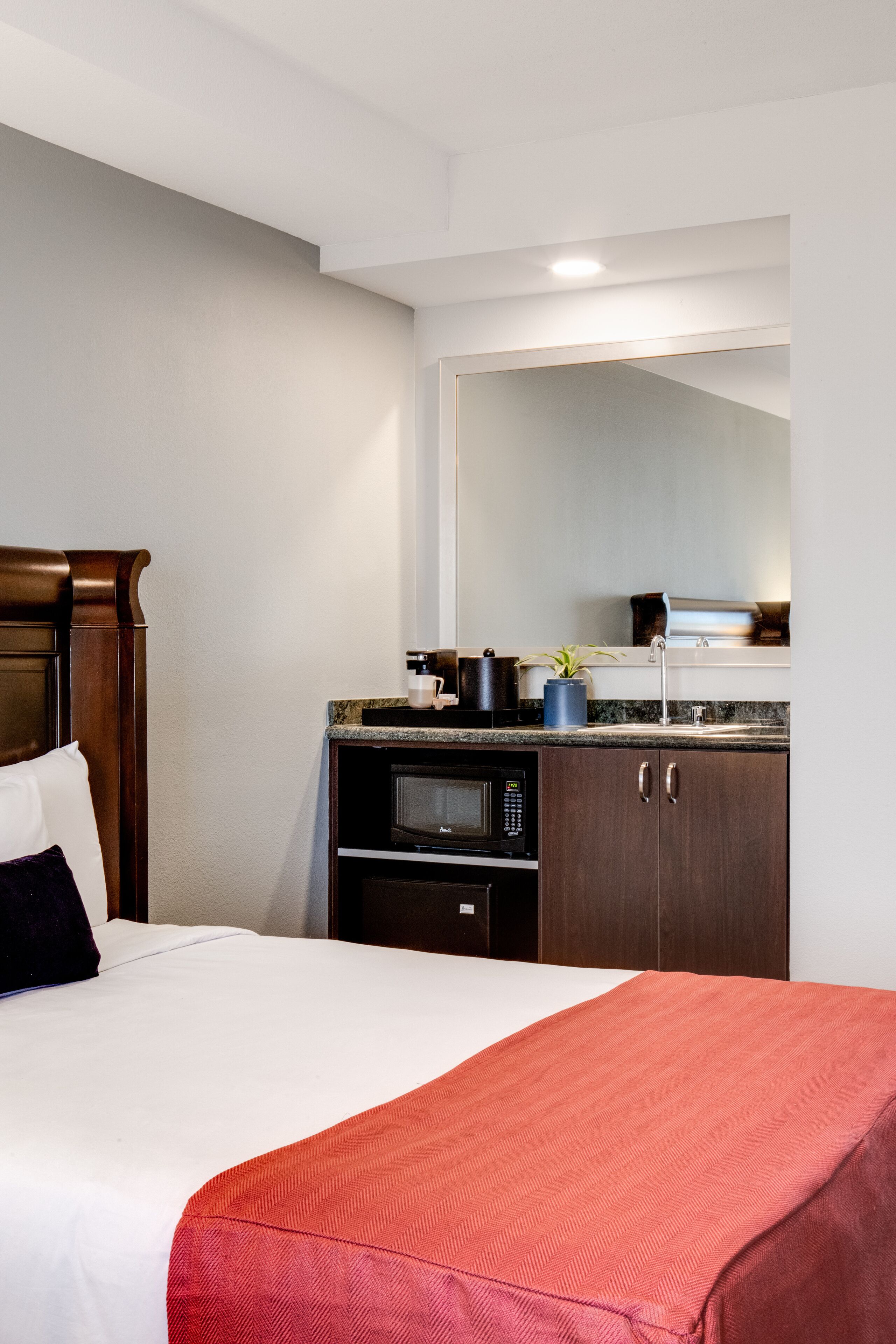 Una habitación de hotel con una cama, microondas, cafetera y un lavabo en la kitchenette.