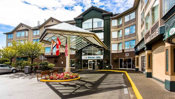 A hotel entrance with a covered lobby area, a flag display, and a "Welcome Lobby" sign.
