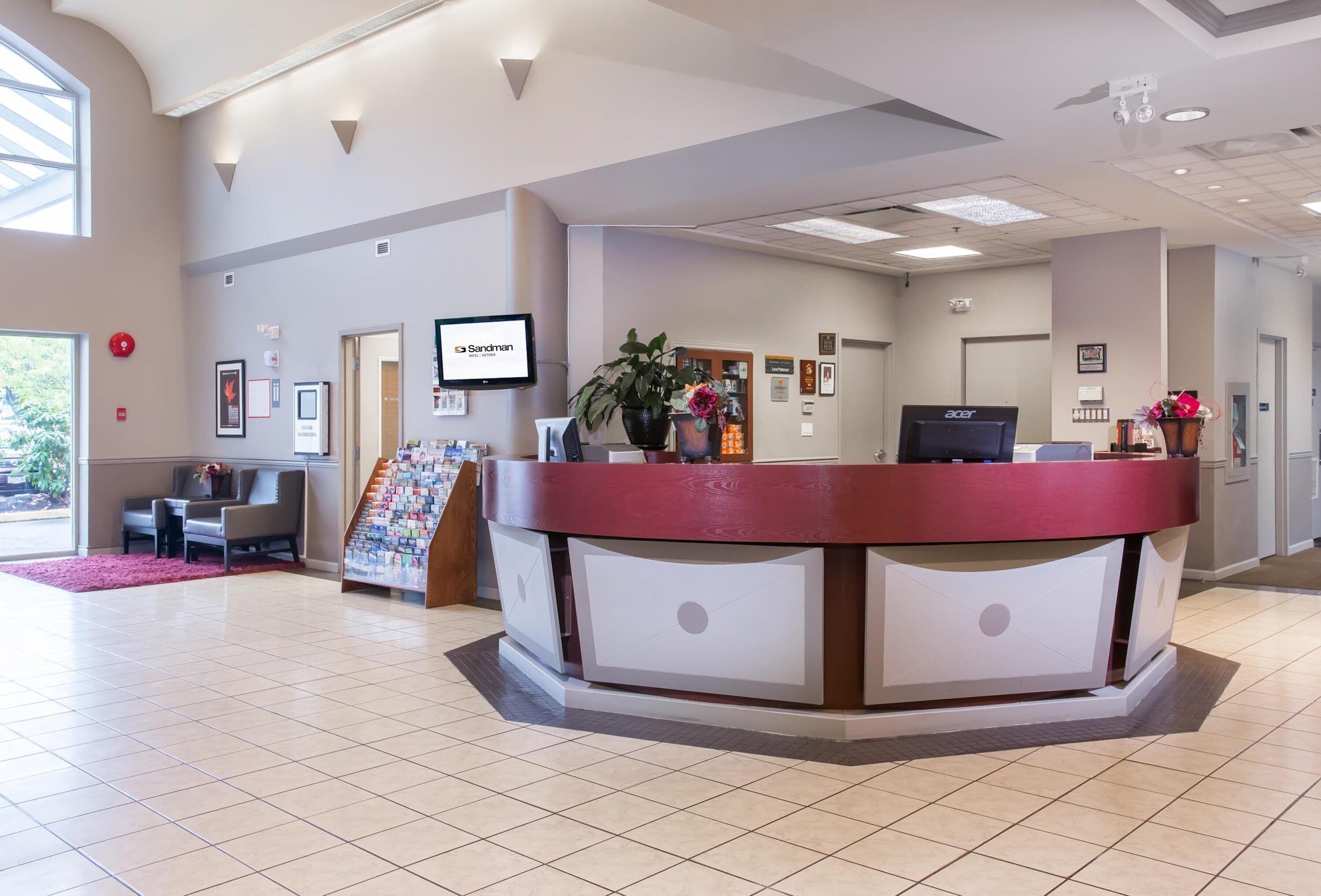 A reception area with a red counter, a television, framed pictures on the wall, and a staircase leading to another floor.