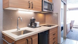 A modern kitchen with wooden cabinets, a stainless steel microwave, a coffee maker, and a dishwasher.