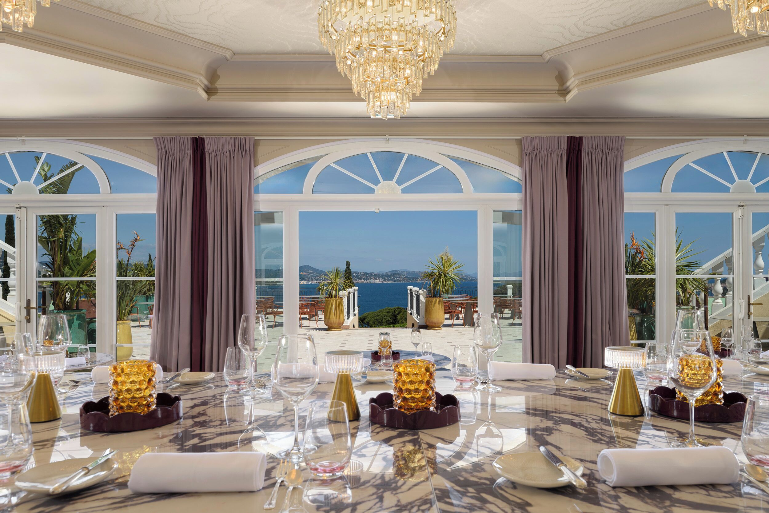 A dining table set for six with a view of the sea.