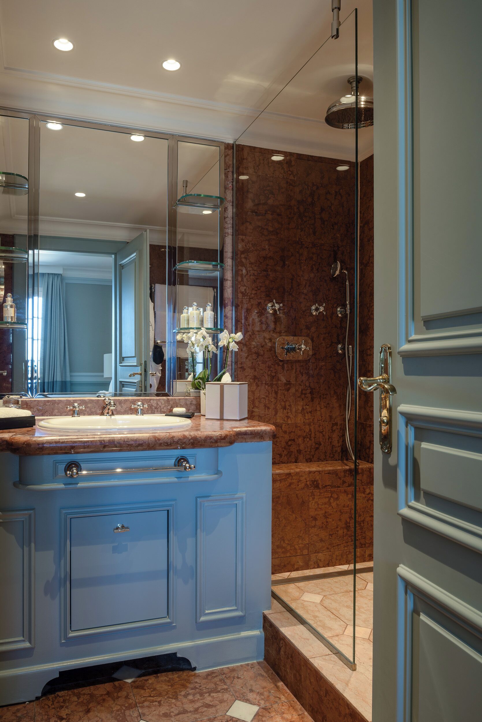 A bathroom with a marble sink, a glass shower enclosure, and a large mirror.