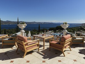 Enjoy the breathtaking sea and mountain views from this outdoor terrace, featuring comfortable seating and a potted plant.