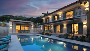 A modern two-story house with a swimming pool, outdoor seating, and a well-lit patio area. - Althoff Hotel Villa Belrose (Gassin)