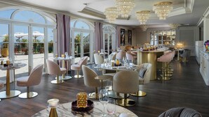 A spacious dining area with round tables, elegant chairs, and chandeliers. - Althoff Hotel Villa Belrose (Gassin)