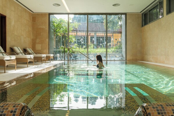 Alberca techada, alberca al aire libre y sombrillas en la alberca