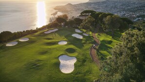 A golf course with bunkers and a path, overlooking a coastal cityscape. - Casa Velha do Palheiro, Relais & Chateaux (Funchal)