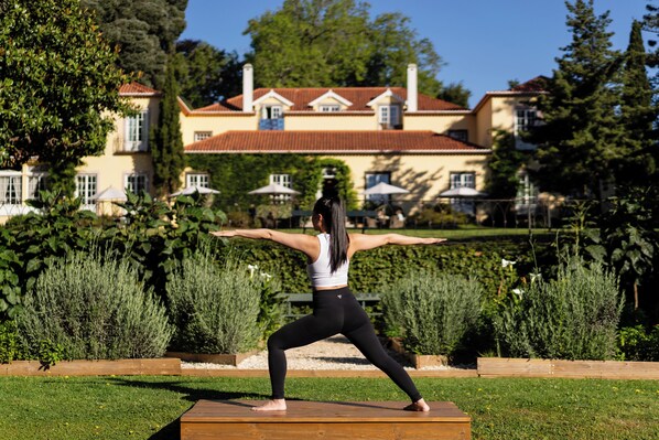 A person performing a yoga pose outdoors with a large building in the background.
