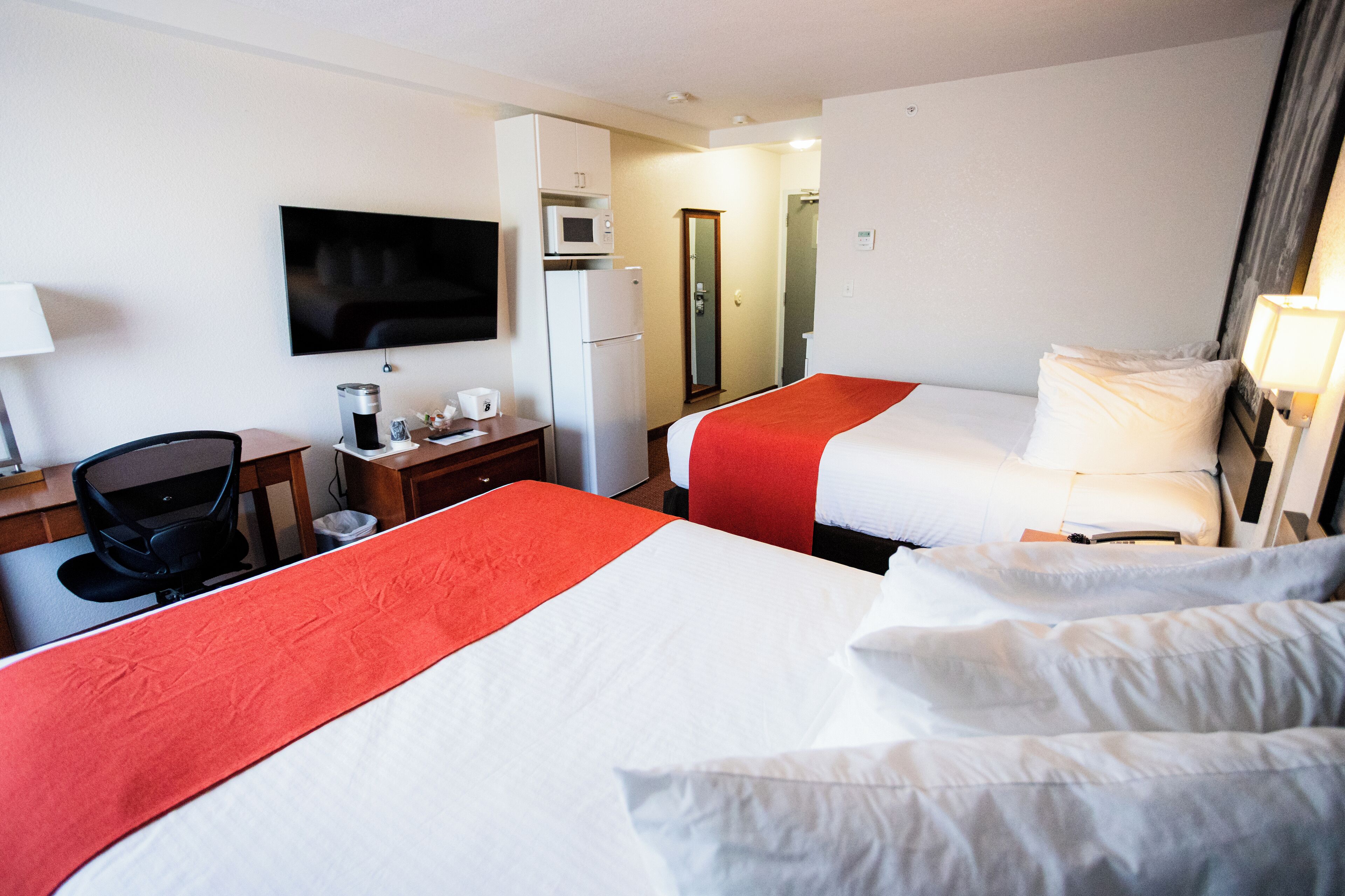 Een hotelkamer met twee bedden, een bureau, een stoel, een televisie, een magnetron en een koelkast.