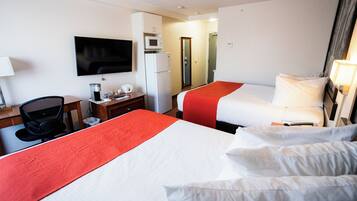 Een hotelkamer met twee bedden, een bureau, een stoel, een televisie, een magnetron en een koelkast.