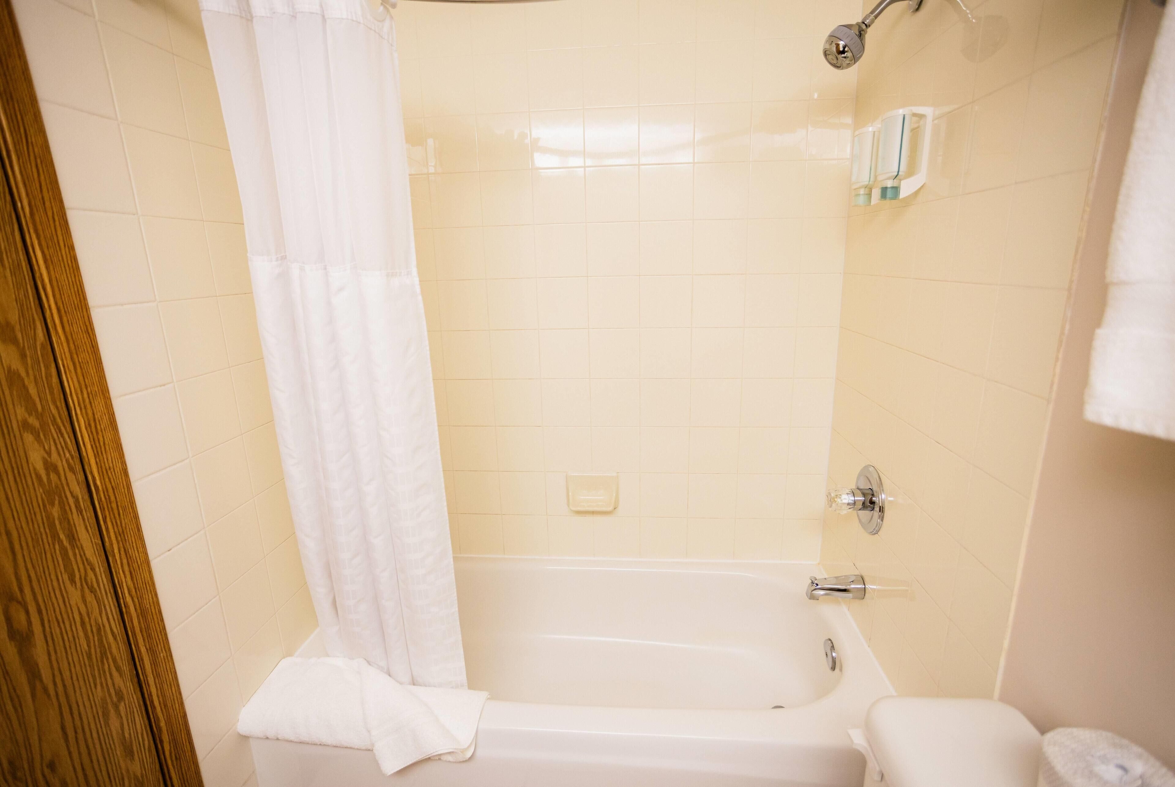 A bathroom with a bathtub, a shower curtain, and a toilet.