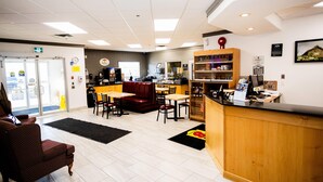 A restaurant interior with a reception desk, seating area, and a counter with various items. - Super 8 by Wyndham Drayton Valley (Drayton Valley)