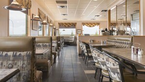 A restaurant with booths and tables, a tiled floor, and a view through the windows. - Super 8 by Wyndham Drayton Valley (Drayton Valley)