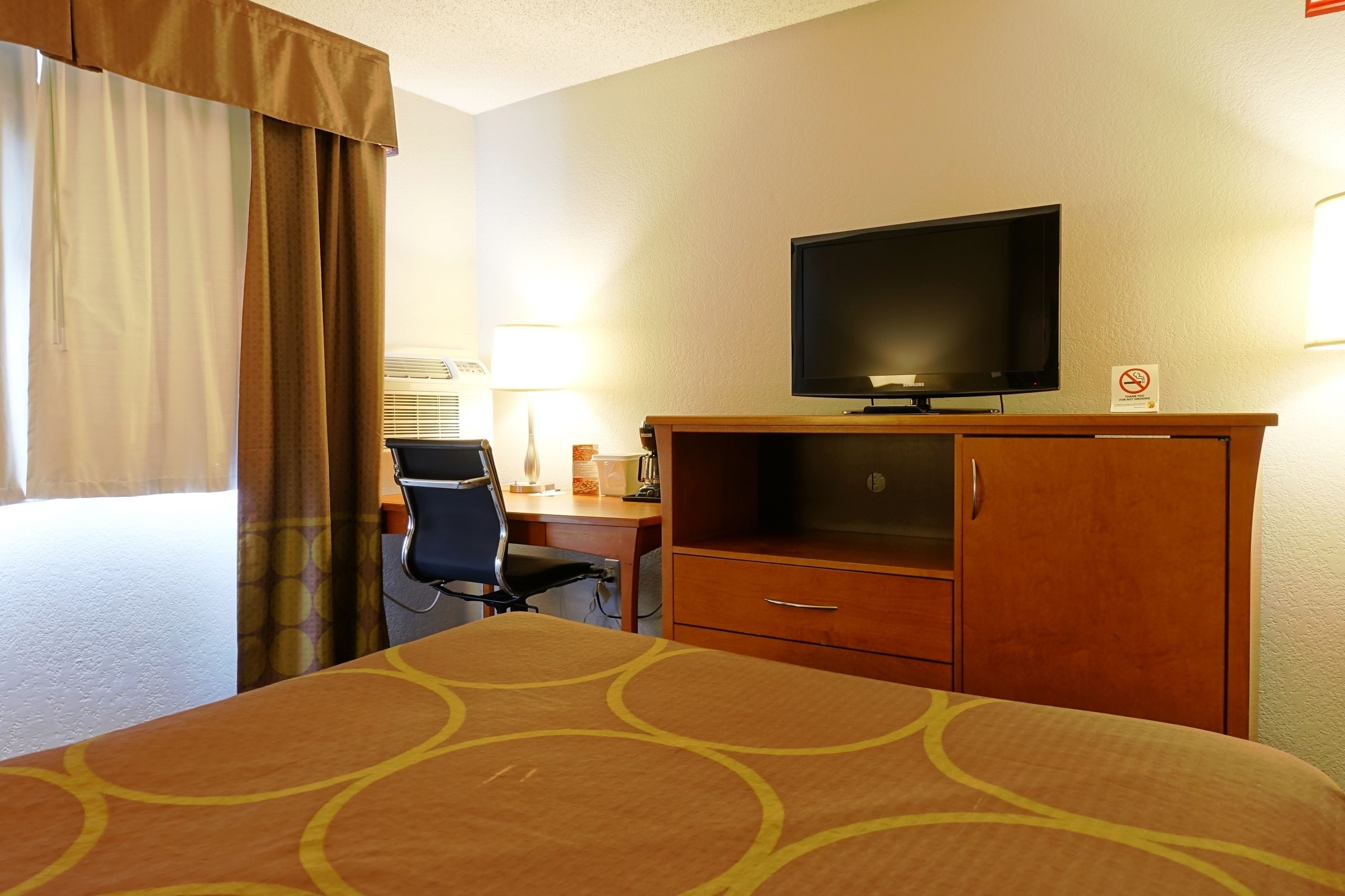 Una habitación de hotel con cama, escritorio, silla, televisión y armario.