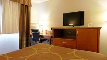 Una camera d'hotel con un letto, una scrivania, una sedia, una televisione e un armadio.