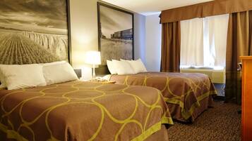 Habitación de hotel con dos camas, un cuadro grande en la pared, una ventana con cortinas y una mesita de noche con lámpara.