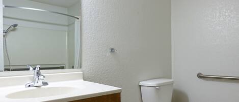 A bathroom with a white sink, a mirror, a toilet, and a shower.