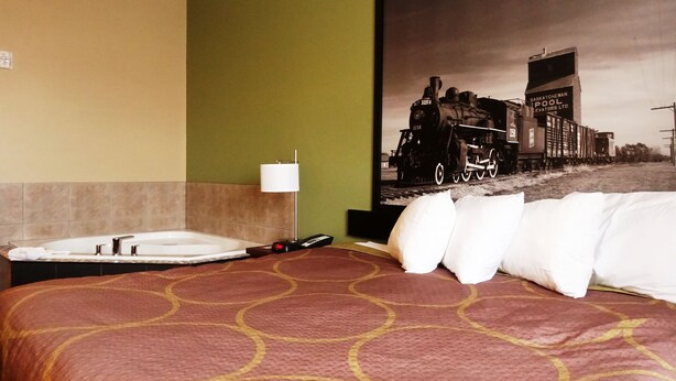 Une chambre d’hôtel avec un lit, un tableau représentant un train, une lampe et une télécommande.