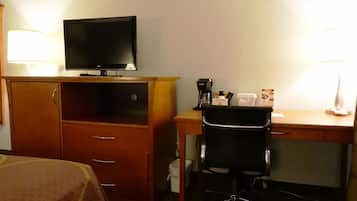 Una habitación de hotel con cama, escritorio con silla, televisor y cafetera.