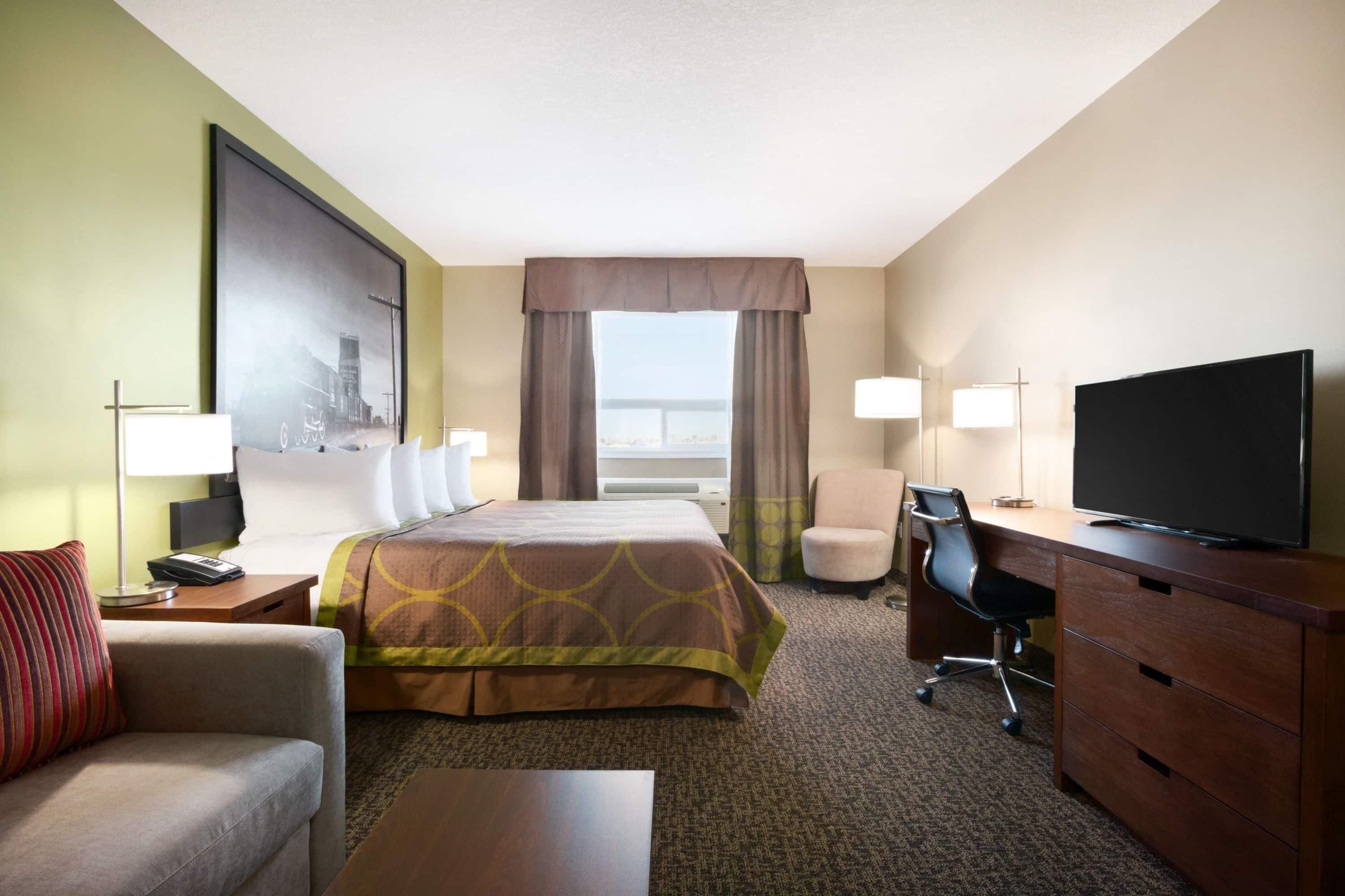 A hotel room with a bed, a desk, a television, a chair, and a couch.