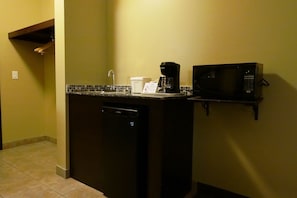 Una kitchenette compacta equipada con cafetera, microondas y lavavajillas.