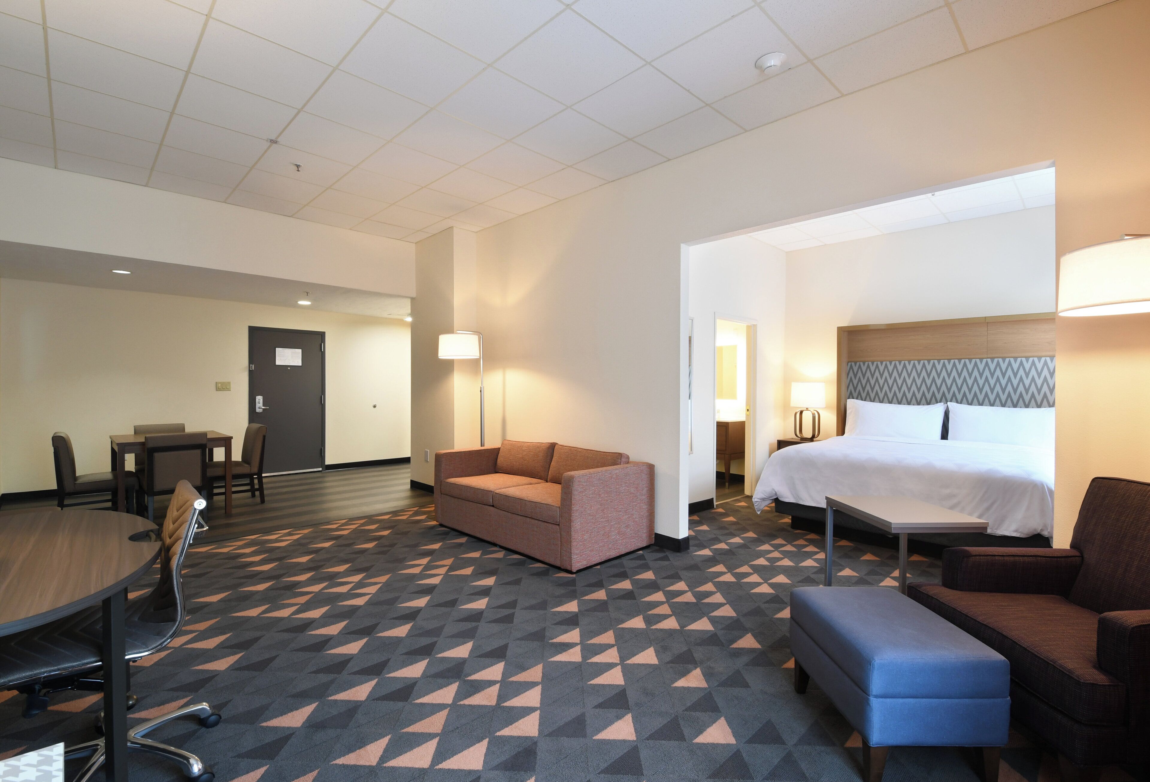 A hotel room with a bed, a sofa, a desk, and a chair.