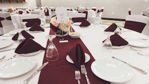 A table set for a formal event with white plates, silverware, and a red table runner. - Holiday Inn Fredericksburg Conference Ctr by IHG (Fredericksburg)