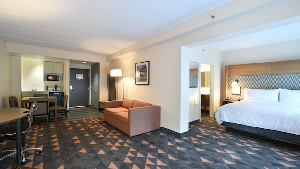 Une chambre d’hôtel comprenant un lit, un bureau avec une chaise, un canapé et une kitchenette.