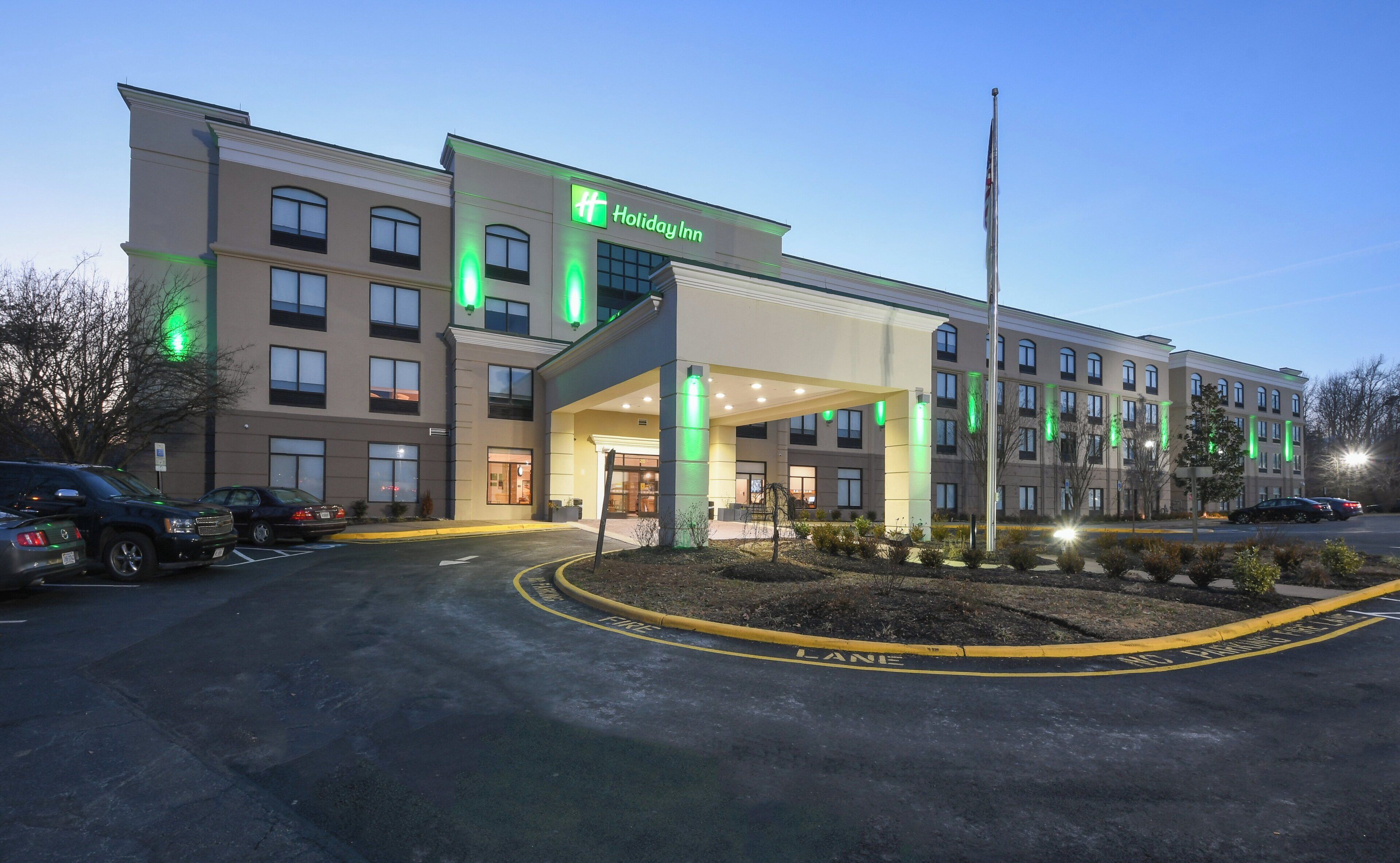 A Holiday Inn hotel with a covered entrance, multiple windows, and a parking lot.