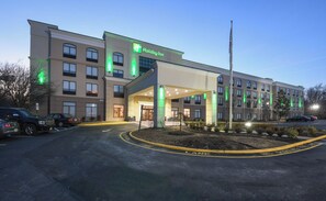 Ein Holiday Inn Hotel mit überdachter Eingangspartie, zahlreichen Fenstern und einem Parkplatz.