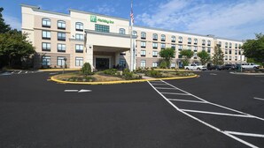 A Holiday Inn hotel with a parking lot and a flag. - Holiday Inn Fredericksburg Conference Ctr by IHG (Fredericksburg)