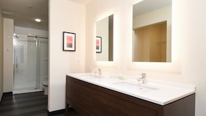 Une salle de bain moderne avec un meuble-lavabo à deux vasques, un grand miroir et une cabine de douche en verre.