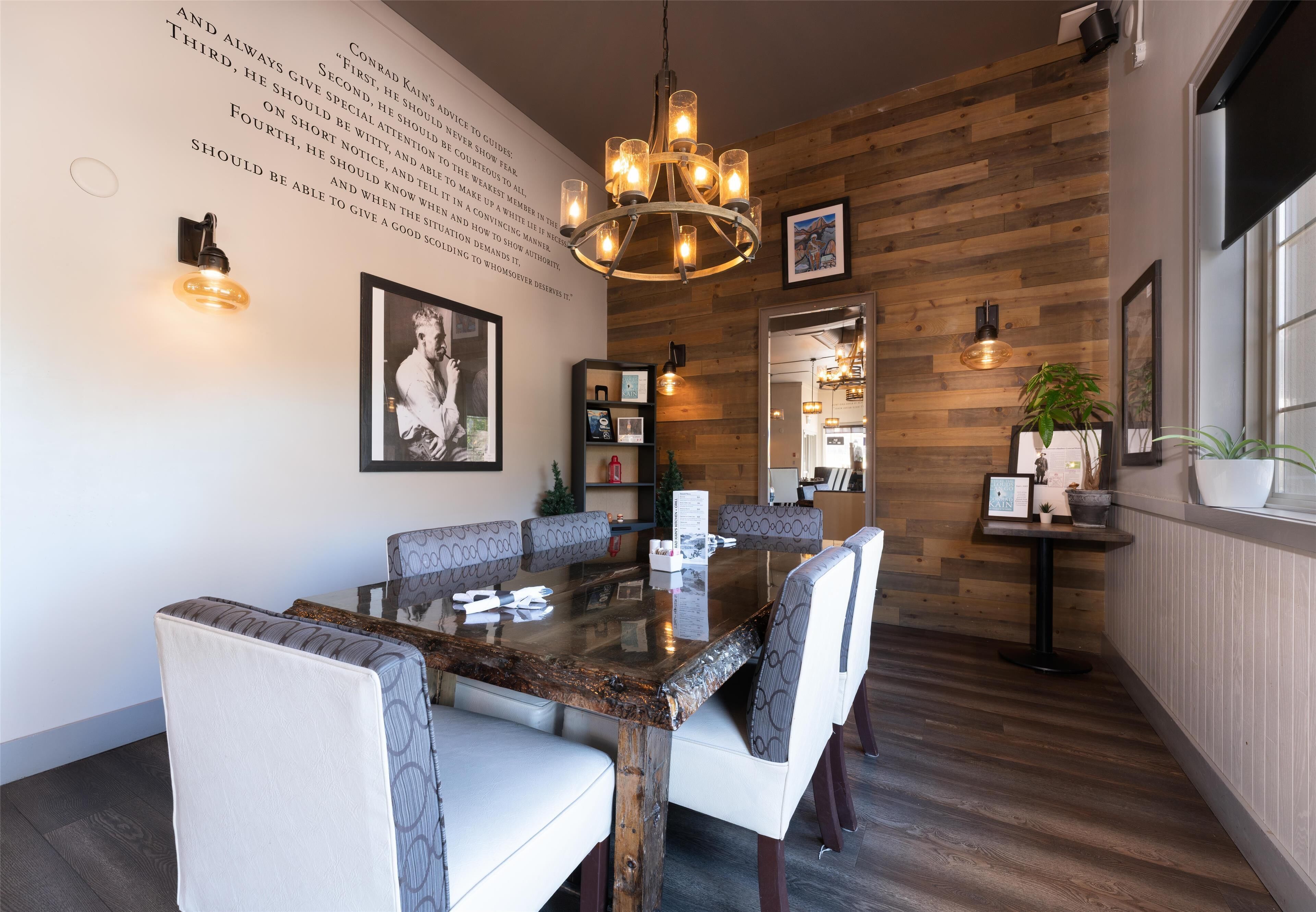 A dining area with a wooden wall, a chandelier, and a table with chairs.