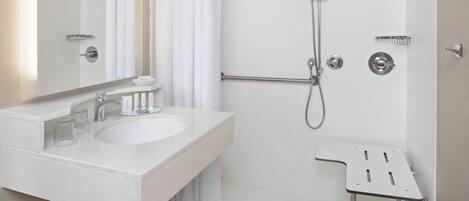 A modern bathroom with a white sink, mirror, and shower.