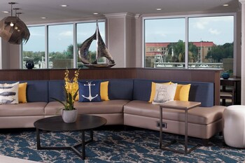 A multi-story hotel with a symmetrical facade, surrounded by lush greenery and a reflective water body. at SpringHill Suites Charleston Riverview 