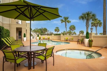 A modern dining area with tables and chairs, large windows, and decorative hanging lights. at SpringHill Suites Charleston Riverview 
